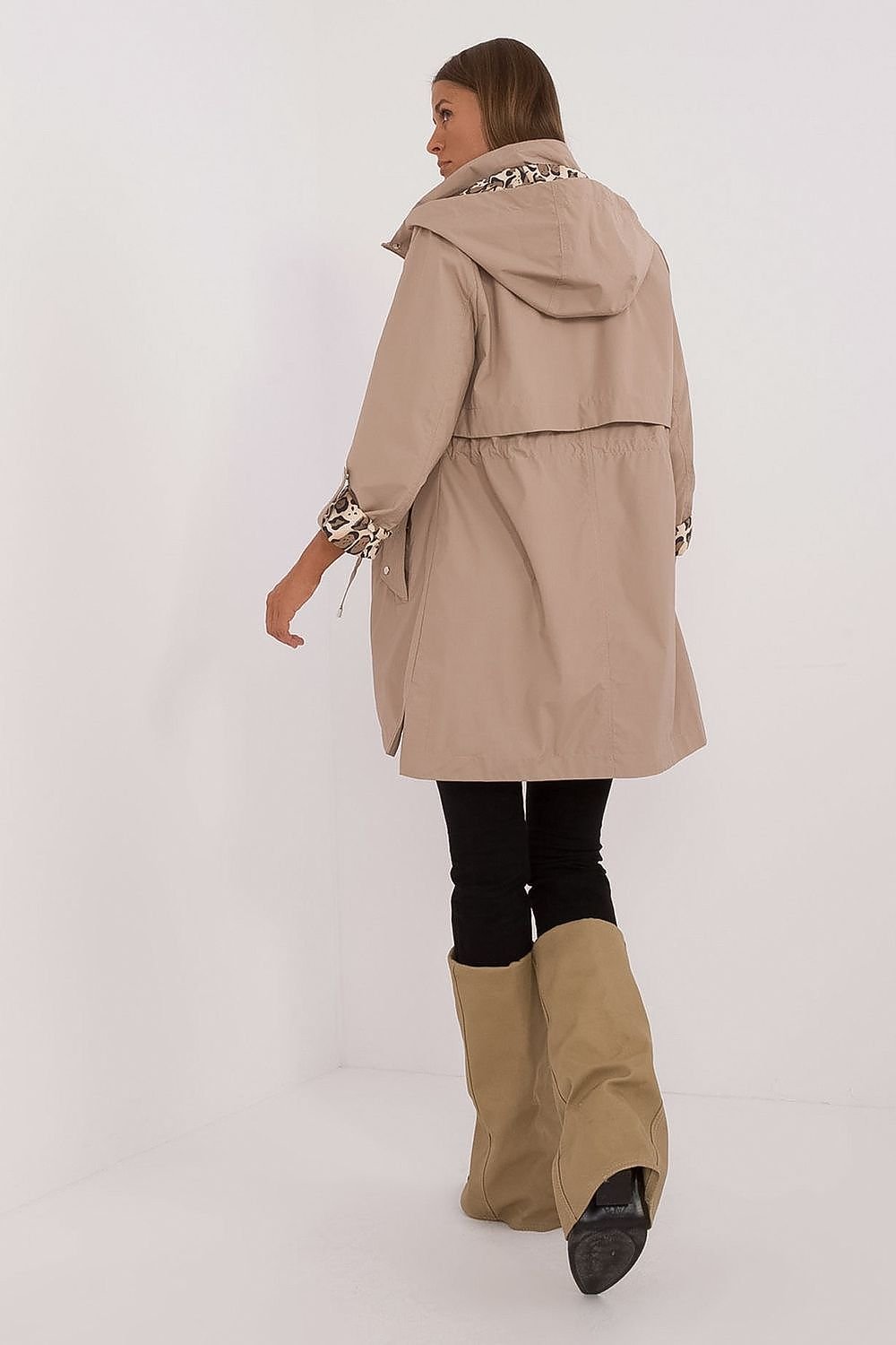Woman wearing a beige trench coat and knee-high boots on a white background
