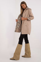 Woman wearing a beige trench coat and high boots on a white background