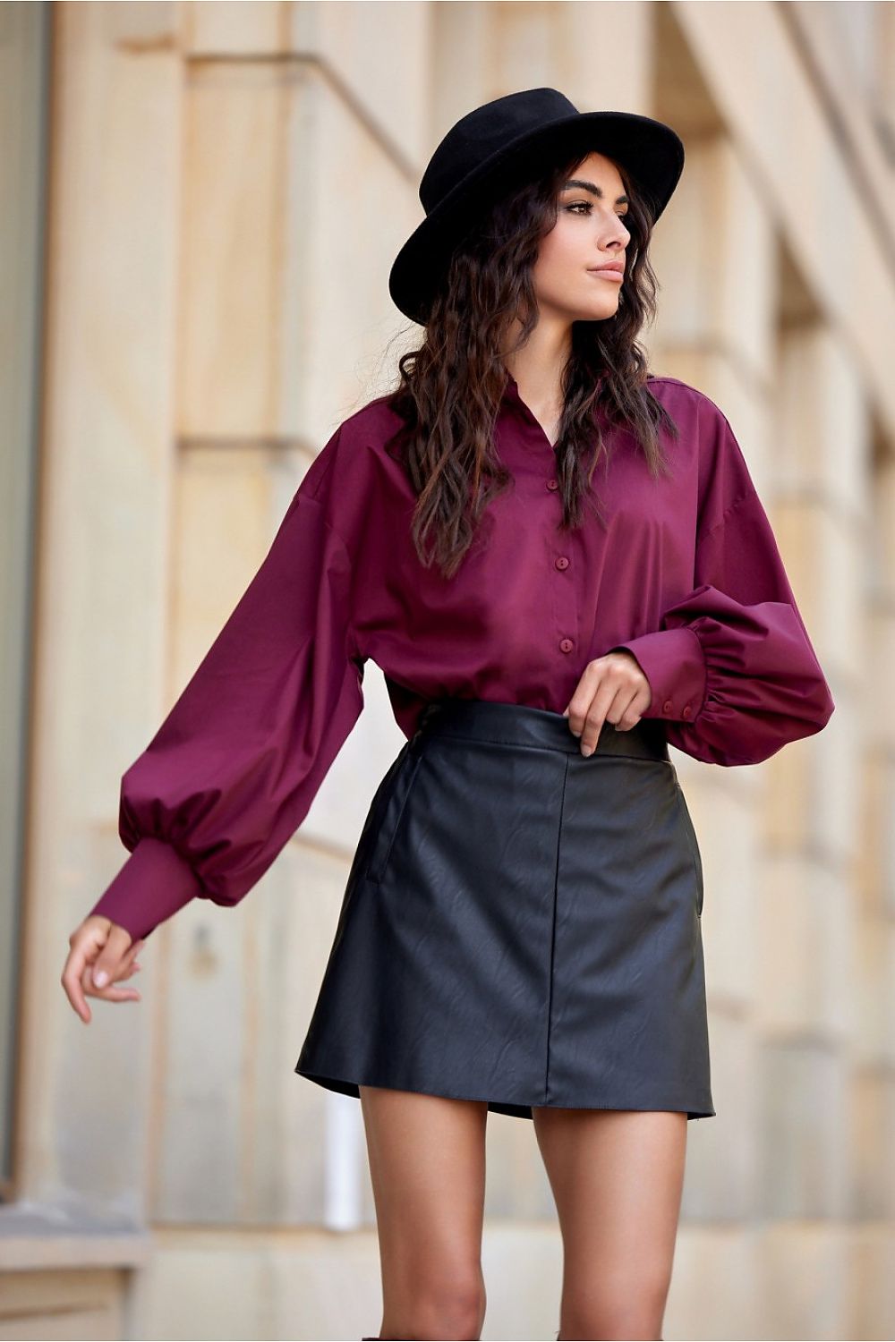 Woman wearing a purple blouse and black skirt with a blurred background