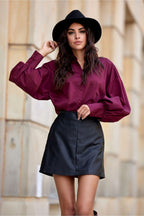 Woman wearing a burgundy shirt and black skirt with a blurred background