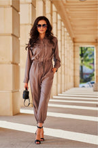 Woman in a brown jumpsuit walking outdoors on a sunny day.