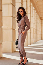 Woman in a gray jumpsuit standing in front of architectural columns