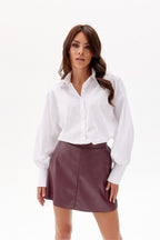 Woman wearing a white blouse and maroon skirt on a white background