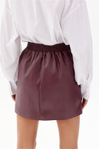 Person wearing a white blouse and maroon skirt on a white background