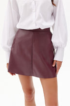 Person wearing a white shirt and burgundy leather skirt on a white background