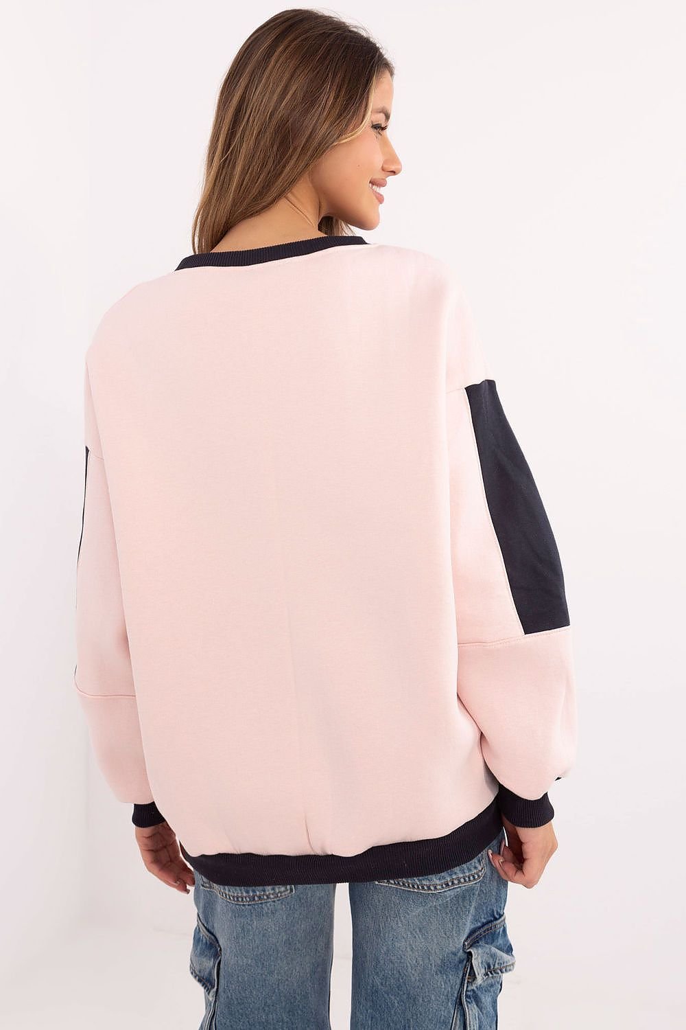 Woman wearing a pink sweater with black sleeves against a white background
