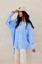 Woman wearing a light blue shirt and beige cap against a plain background