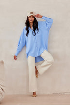 Woman wearing a light blue shirt and white pants against a beige background