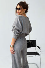 Woman wearing a gray outfit with sunglasses against a white background