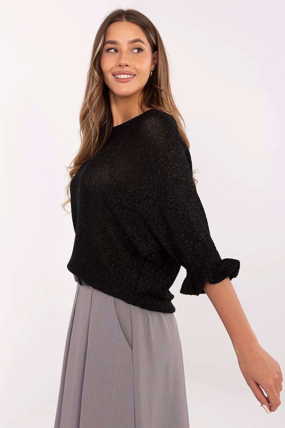 Woman wearing a black sweater and gray pants on a white background