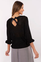 Woman wearing a black sweater with a bow detail on the back against a white background