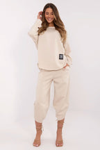 Woman wearing a beige tracksuit with a logo on a white background