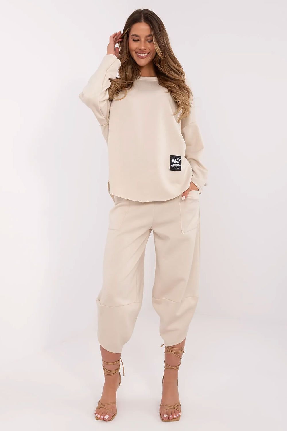 Woman wearing a beige tracksuit with a logo on a white background