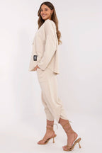 Woman wearing a beige suit with high-heeled sandals on a white background