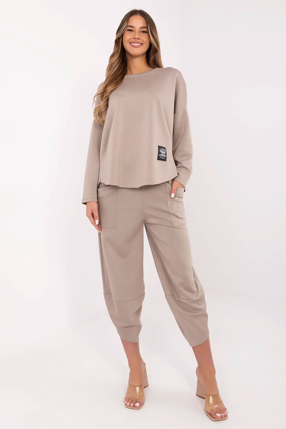 Woman wearing a beige outfit with a logo on a white background