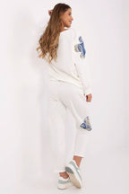 Woman wearing a white outfit with blue designs on a white background
