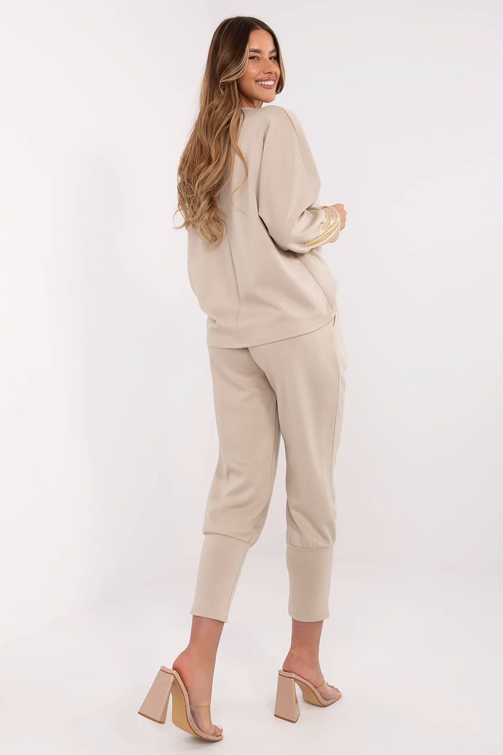 Woman wearing a beige outfit with matching shoes on a white background