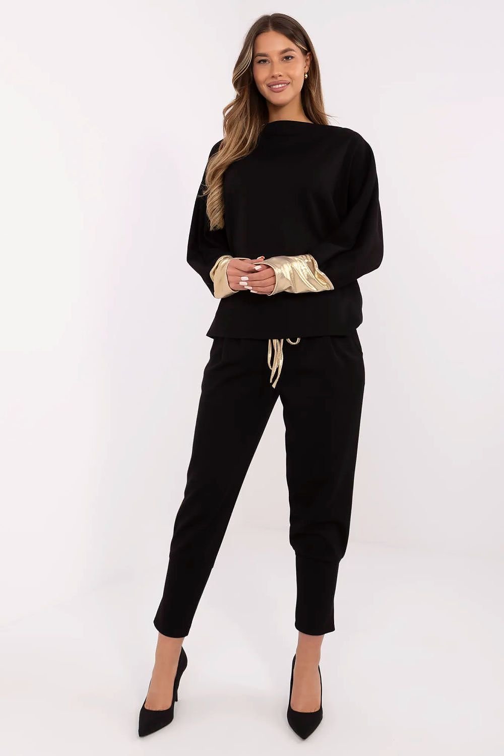 Woman wearing a black outfit with gold accents on a white background