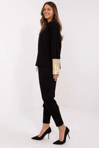 Woman wearing a black outfit with gold accents on a white background