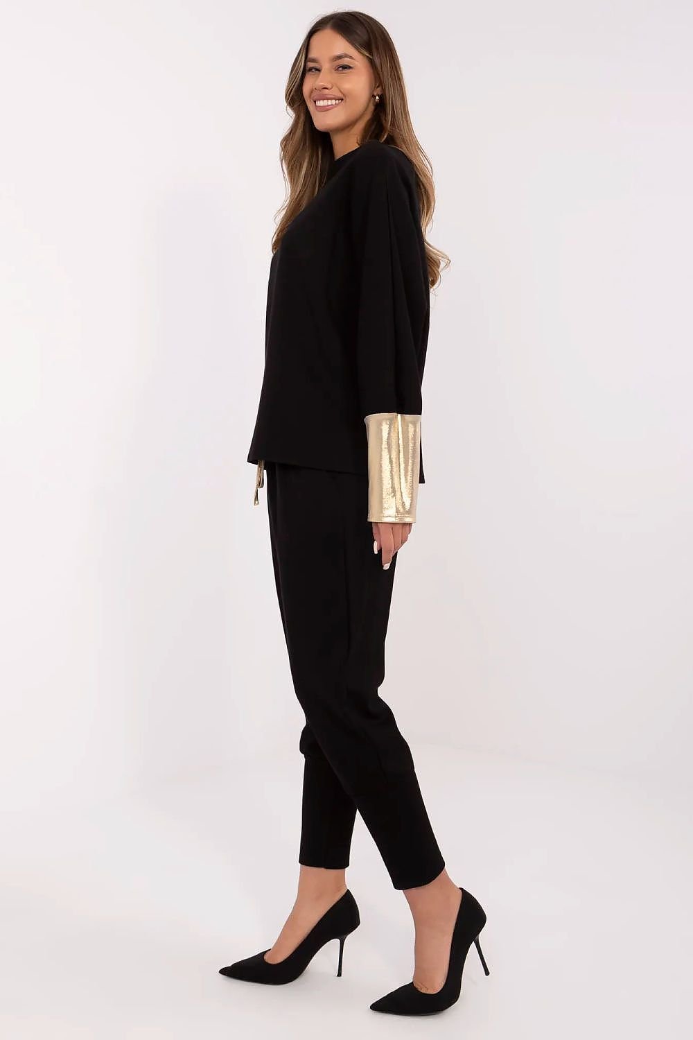 Woman wearing a black outfit with gold accents on a white background