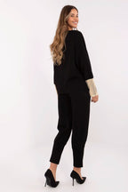 Woman wearing a black outfit with gold cuffs on a white background