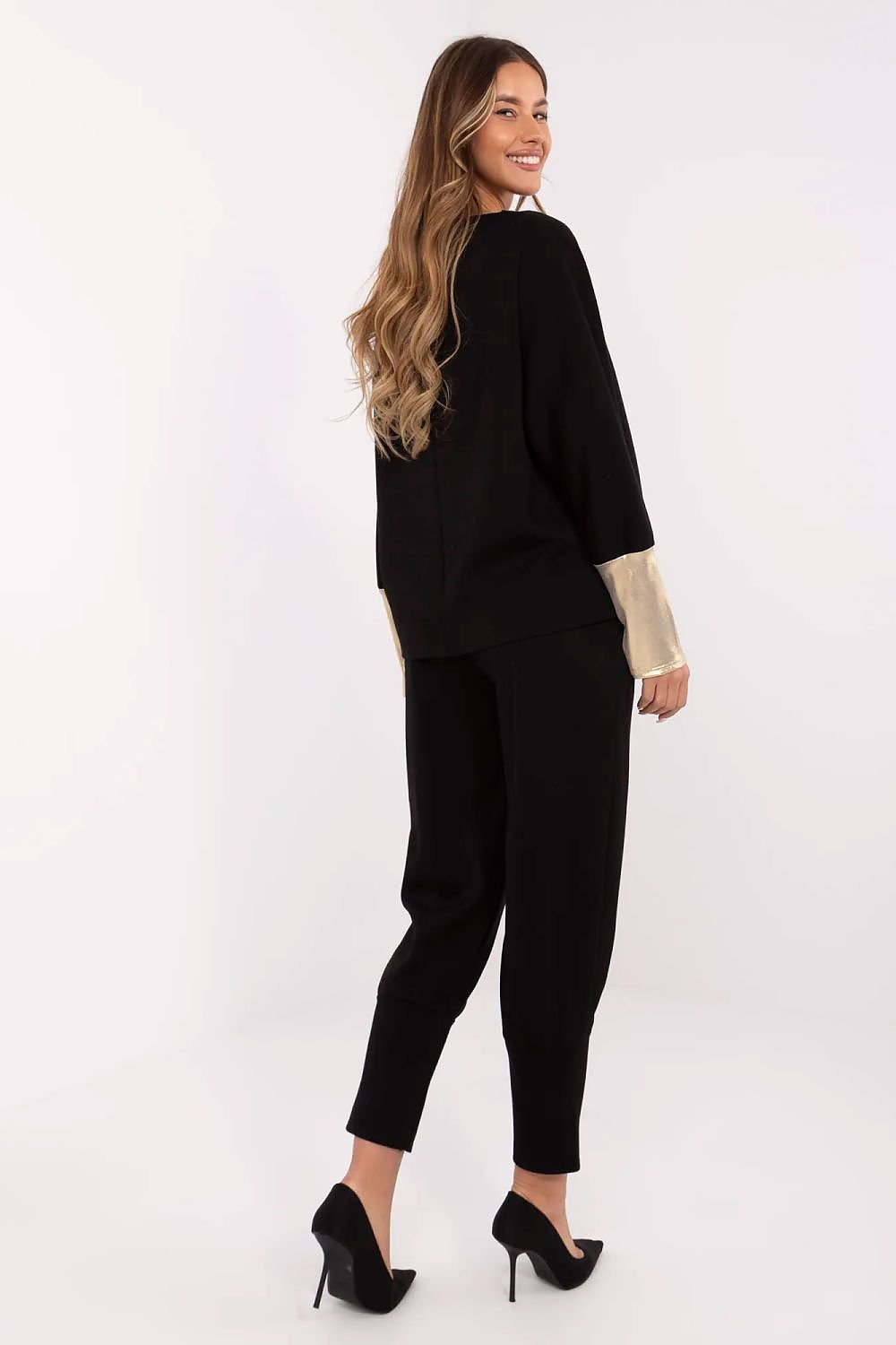 Woman wearing a black outfit with gold cuffs on a white background