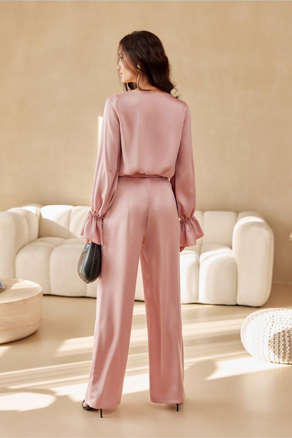 Woman in a pink outfit standing in a modern living room.