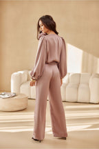 Woman in a pink outfit standing in a stylish room with beige walls and furniture.