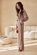 Woman in a beige outfit standing in a modern living room.
