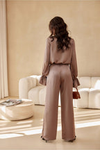 Woman in a beige outfit standing in a living room with a neutral color palette.