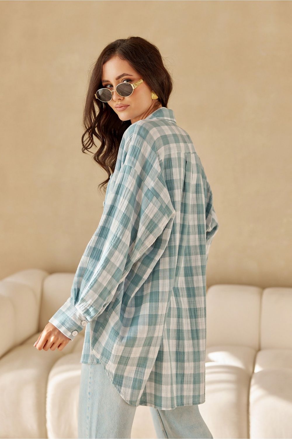 Woman wearing a blue plaid shirt and sunglasses indoors.