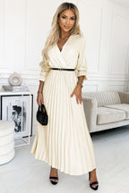 Woman in a white pleated dress standing in a modern living room.