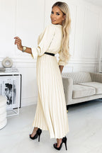Woman in a long white dress standing in a modern living room.