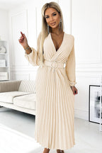 Woman wearing a beige pleated dress in a modern living room.