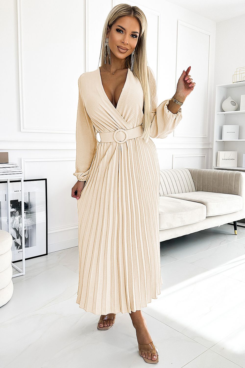 Woman wearing a beige pleated dress in a modern living room.