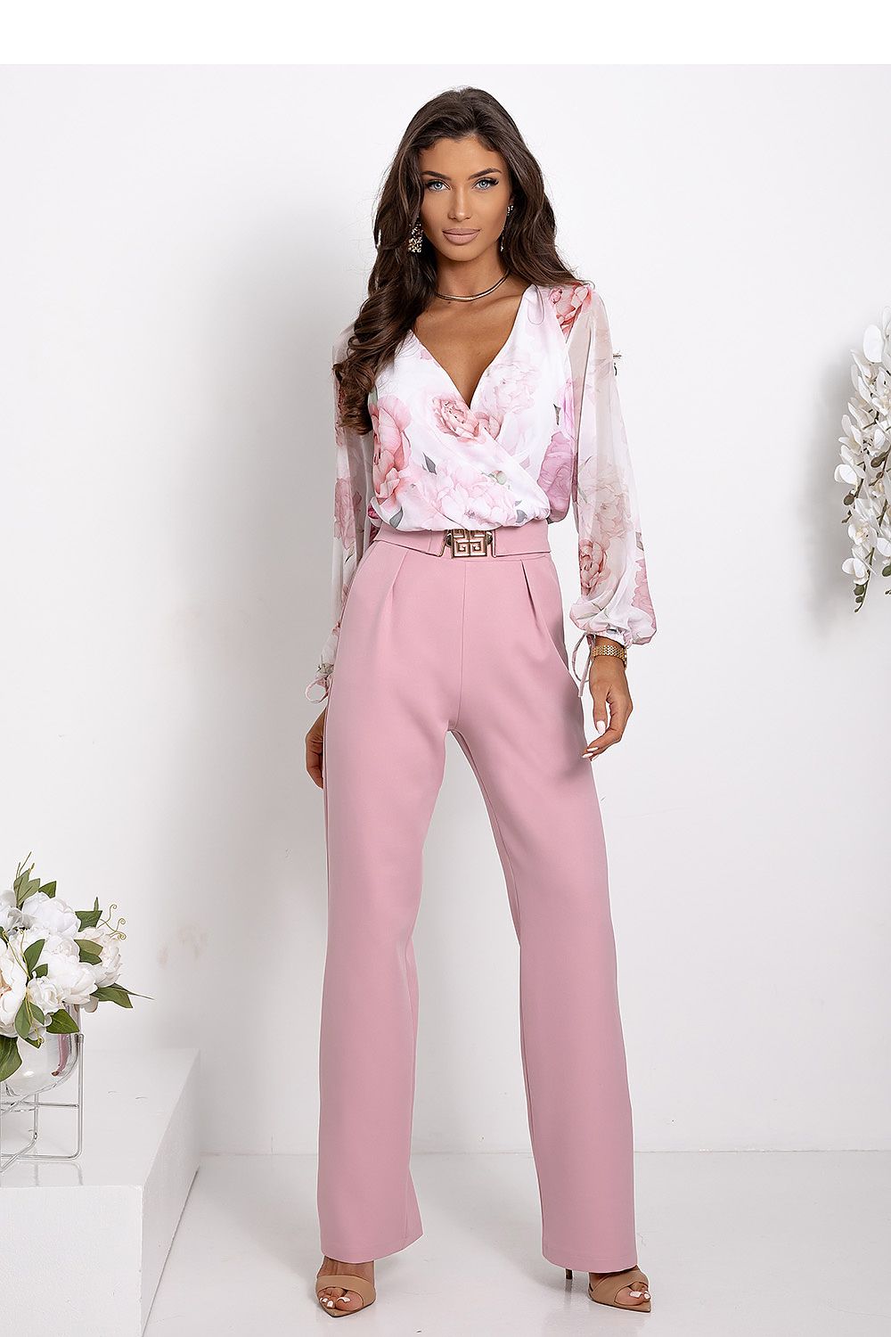 Woman wearing a pink floral blouse and pink pants on a white background