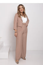 Woman wearing a beige suit with a white top on a white background