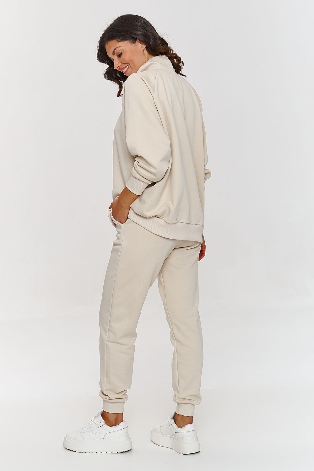 Woman wearing a beige tracksuit on a white background