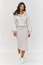Woman wearing a light gray outfit with a jacket and skirt on a white background