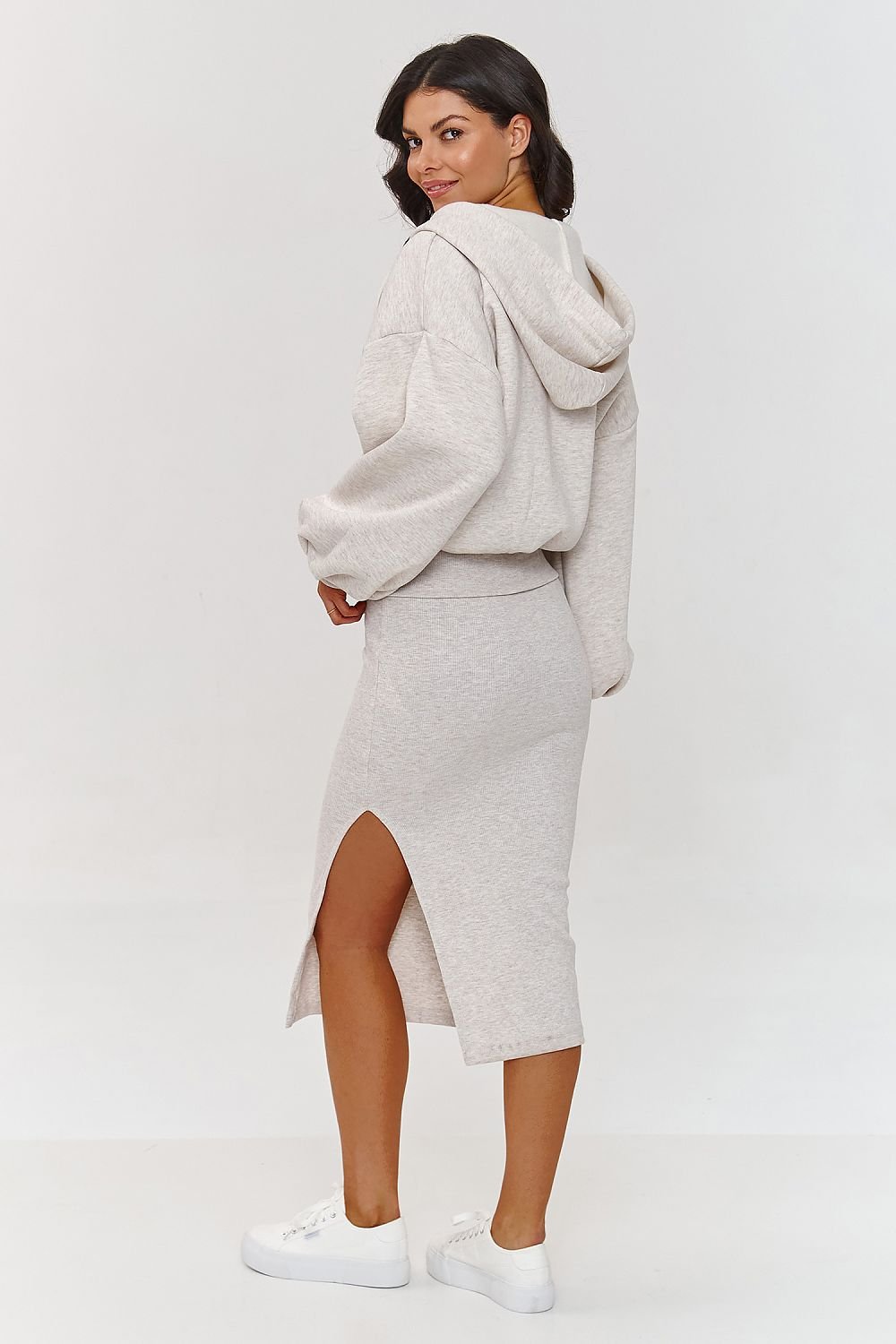 Woman wearing a gray hoodie and skirt set on a white background