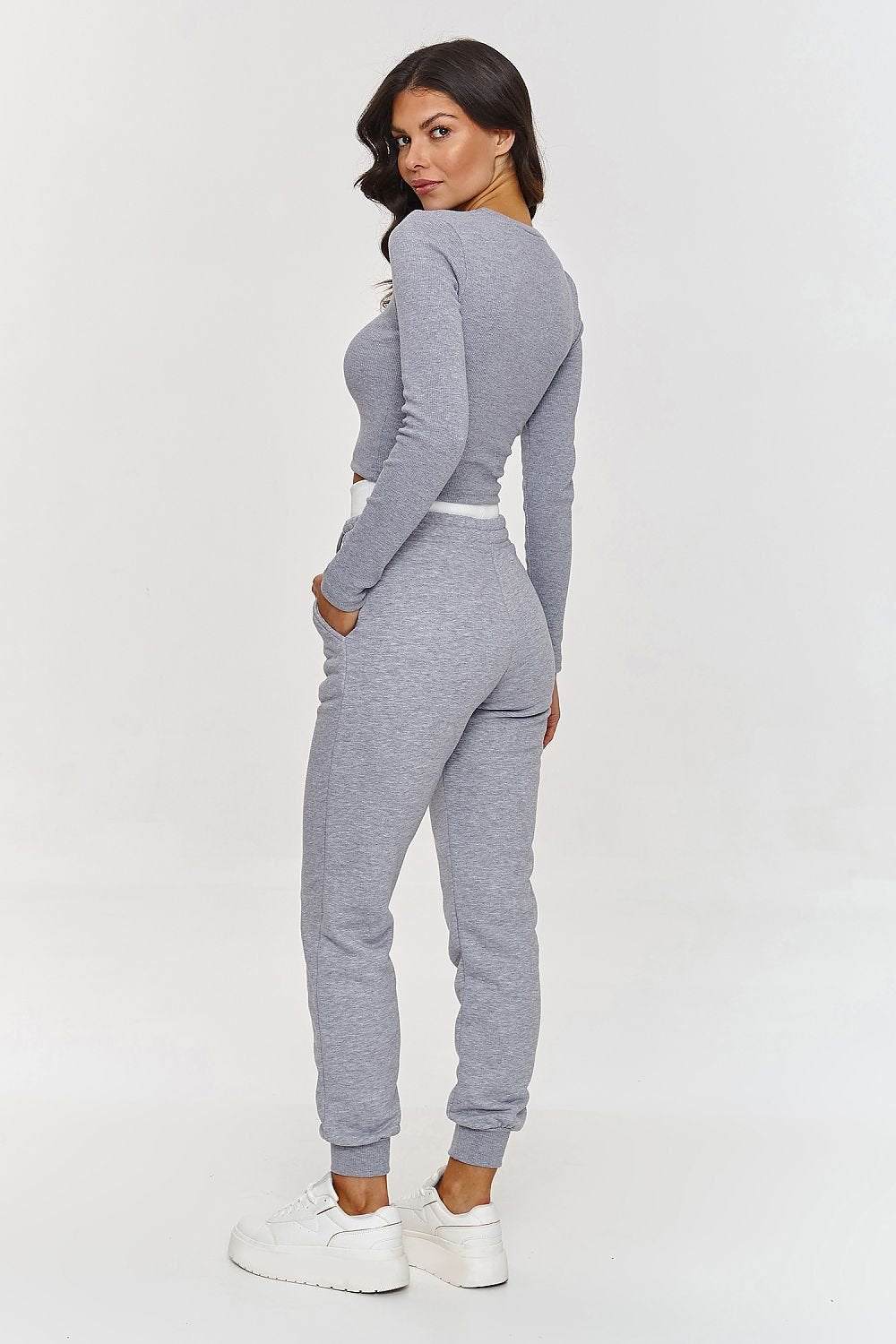 Woman wearing a gray tracksuit on a white background