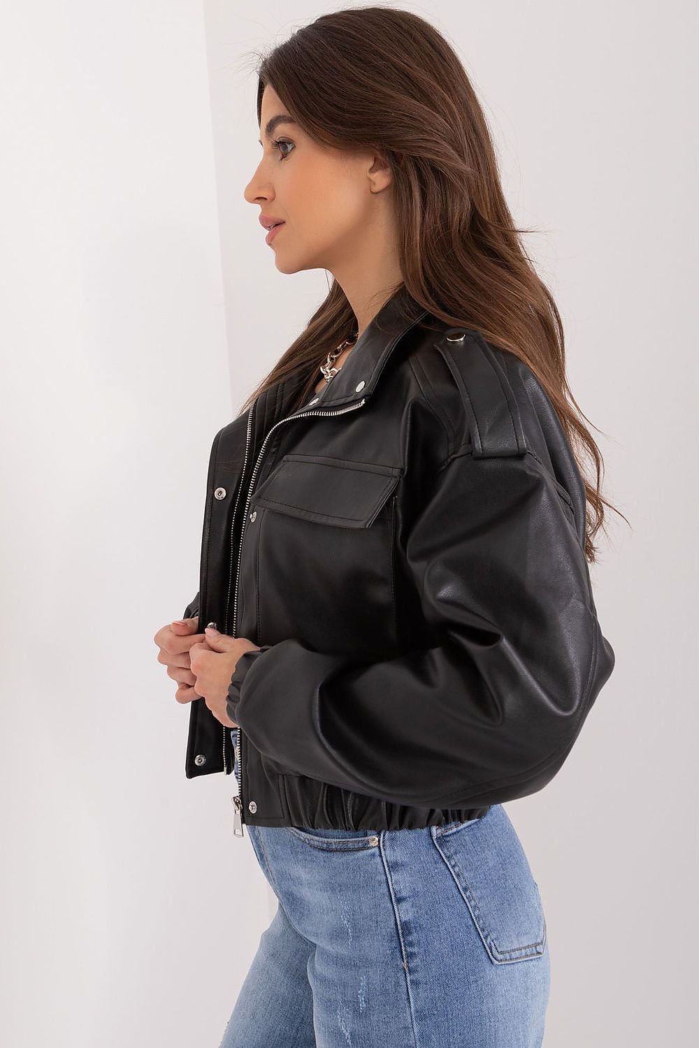Woman wearing a black leather jacket and blue jeans on a white background