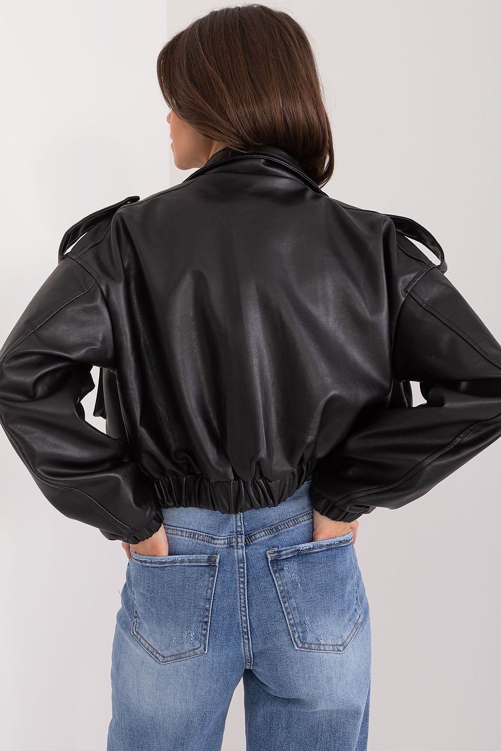 Person wearing a black leather jacket and blue jeans on a white background
