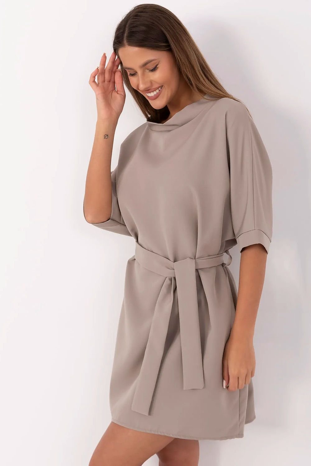 Woman wearing a beige dress with a belt on a white background