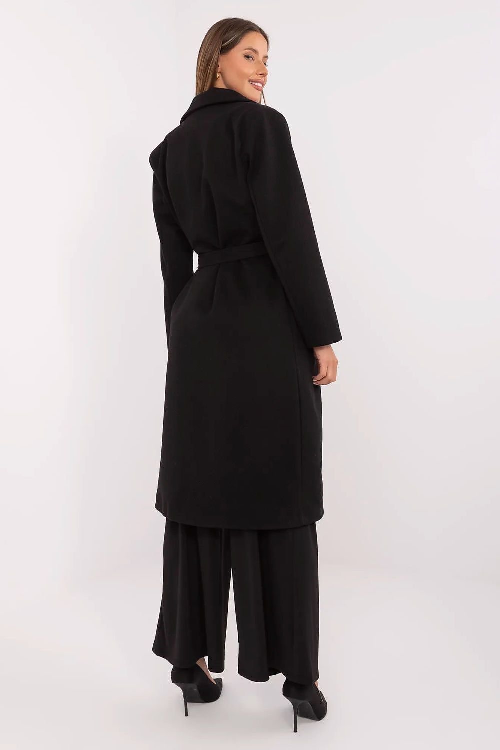 Woman wearing a black coat and pants on a white background