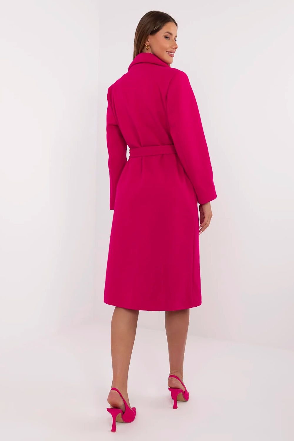 Woman wearing a bright pink coat on a white background