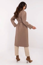 Woman wearing a long beige coat on a white background