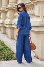 Woman in a blue outfit standing against a beige architectural wall.