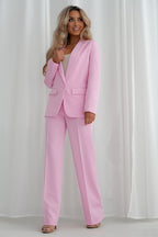 Woman wearing a pink suit against a white curtain background