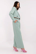 Woman wearing a light green suit with pink shoes on a white background